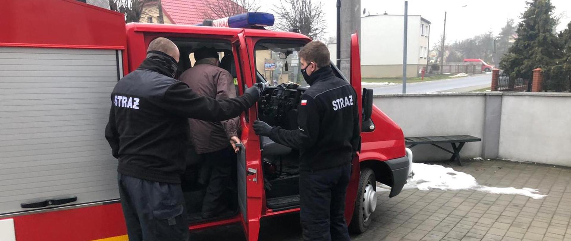 pomoc w transporcie przez strażaków starszemu mężczyźnie