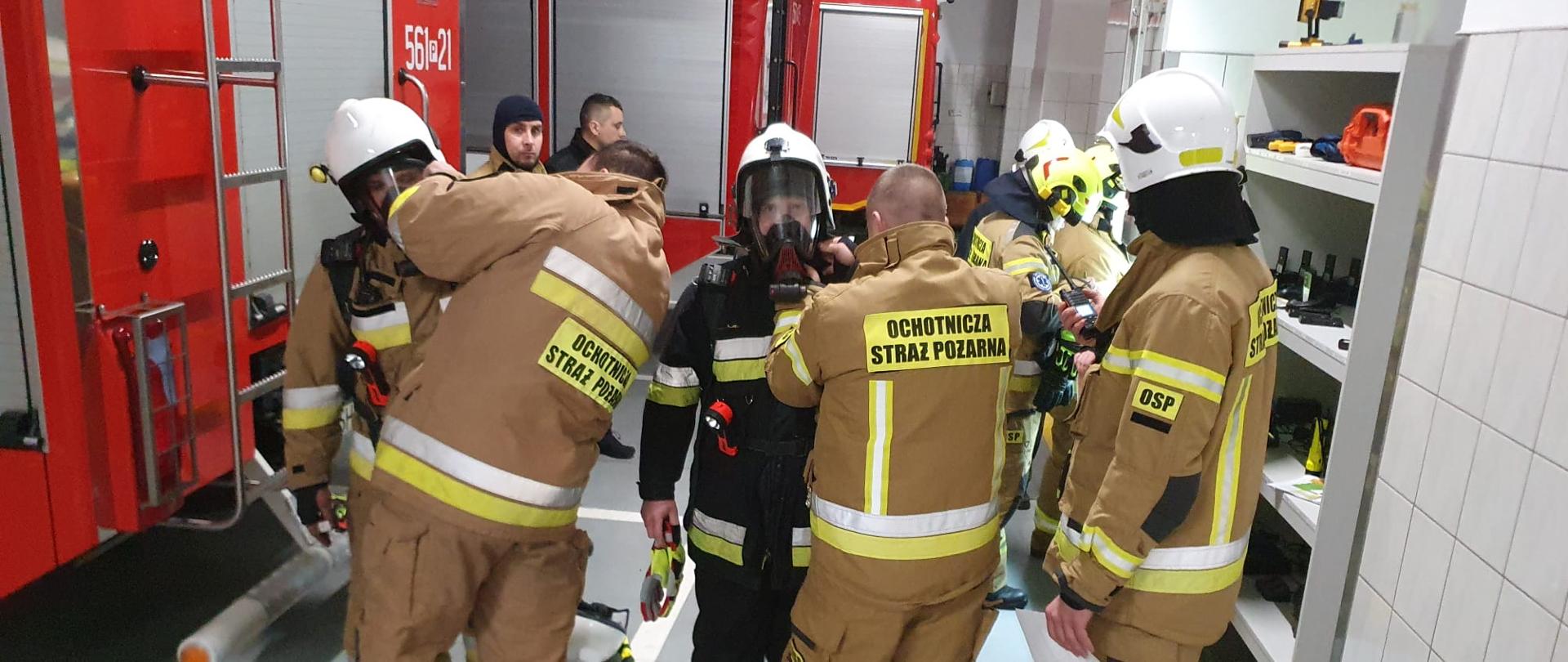 W garażu strażacy ubierają się w aparaty ochrony dróg oddechowych