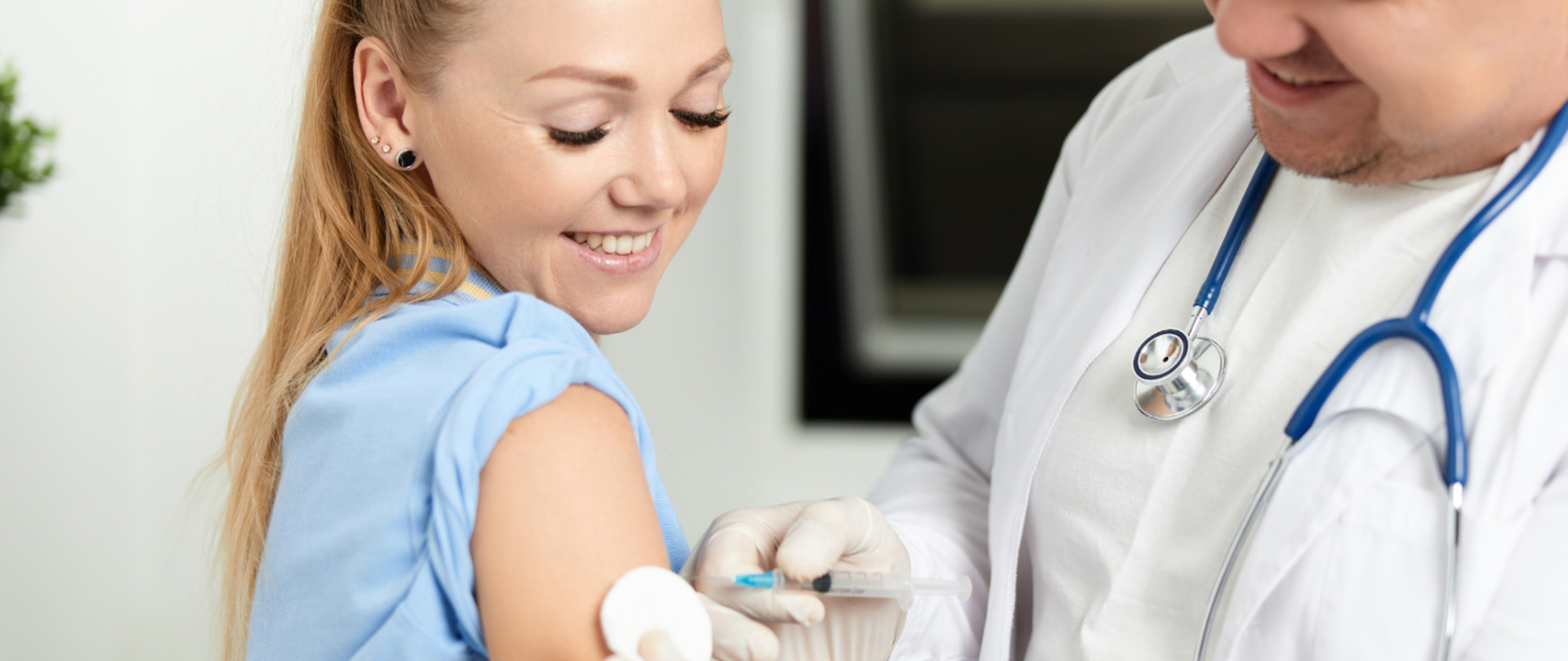 lekarz trzymający w dłoni strzykawkę dokonujący szczepienia kobiety