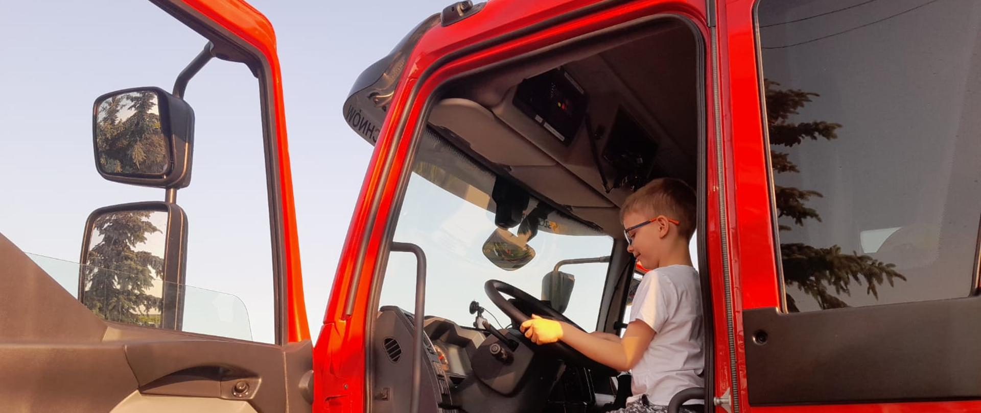 Zdjęcie w ciągu dnia. Światło naturalne. Widać samochód ratowniczo-gaśniczy w kolorze czerwonym.