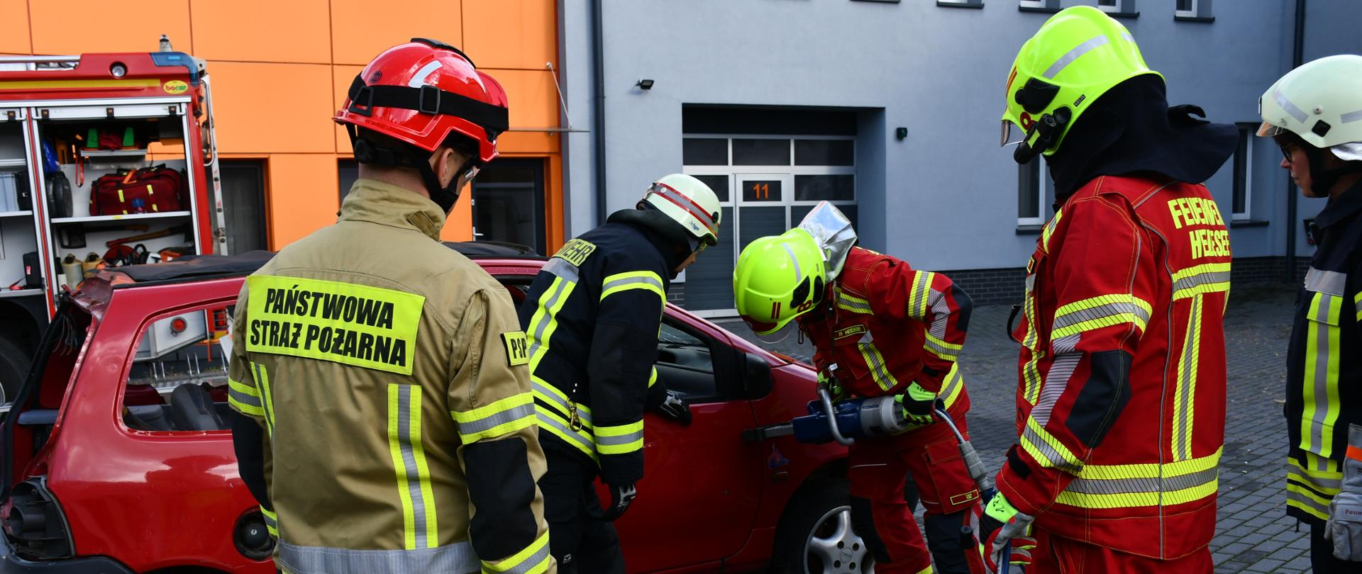 Strażacy z Dahme-Spreewald wykonuja dostęp do pojazdu pod nadzorem strażaka PSP.