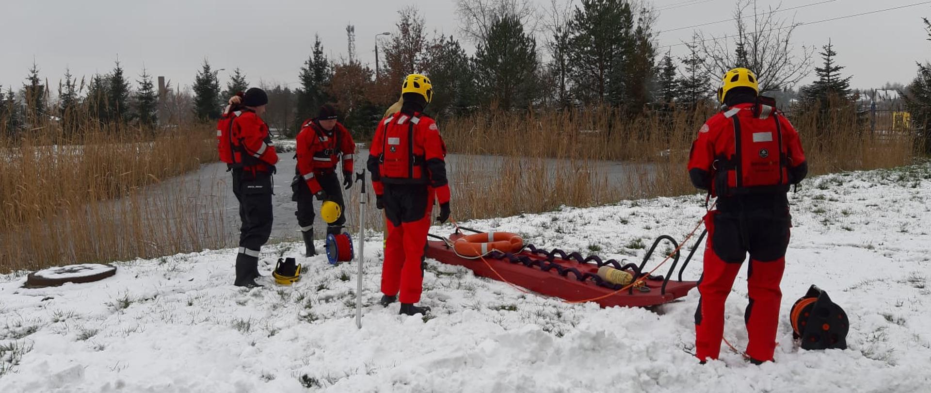 Strażacy ubrani w ubrania do pracy w wodzie przygotowują sprzęt do wejścia do wody