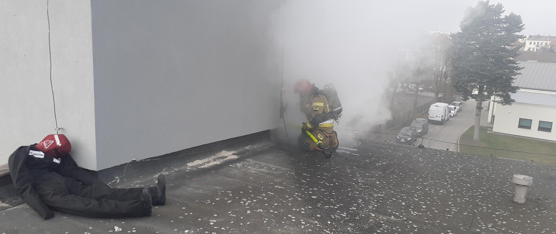 Strażak na dachu w zadymieniu