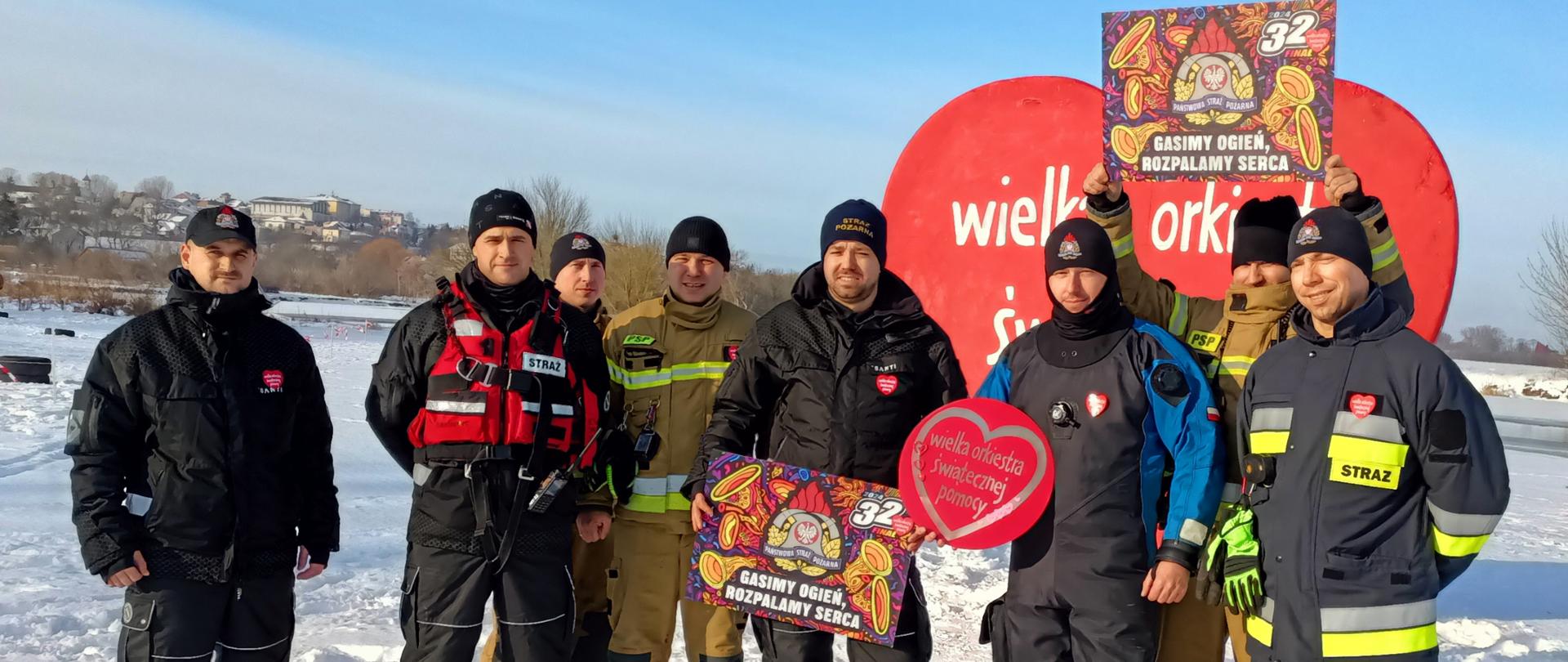 strażacy stoją przy dużym sercu WOŚP 