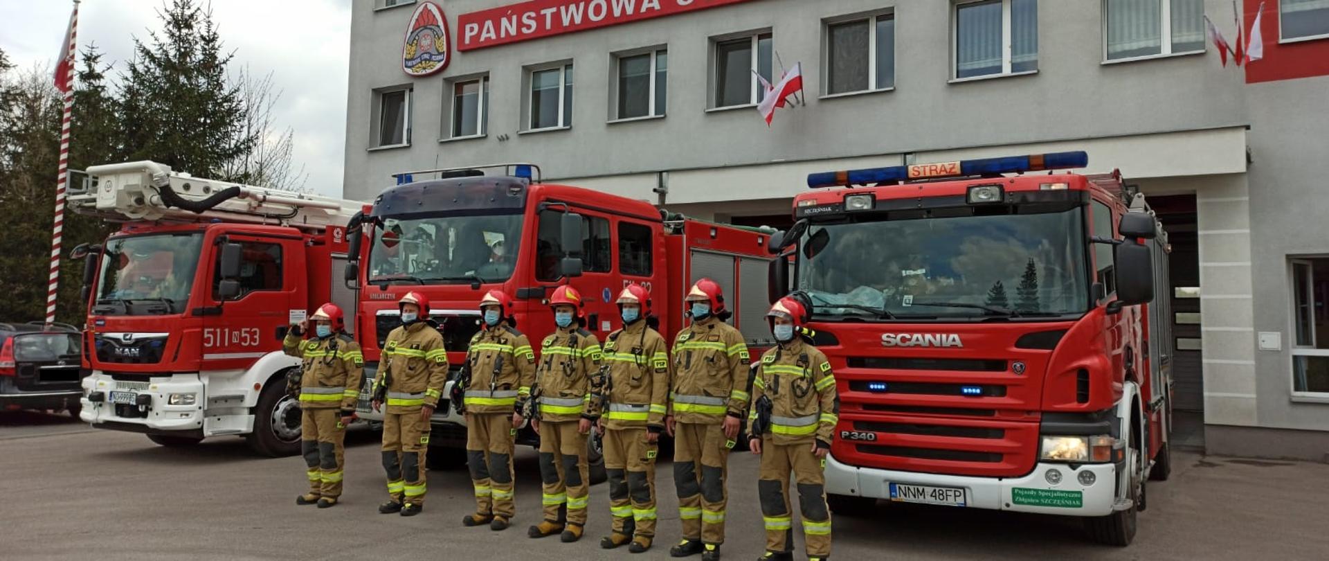 Zmiana służbowa oddaje hołd poległemu na służbie funkcjonariuszowi policji. 3 wozy strażackie na tle komendy 