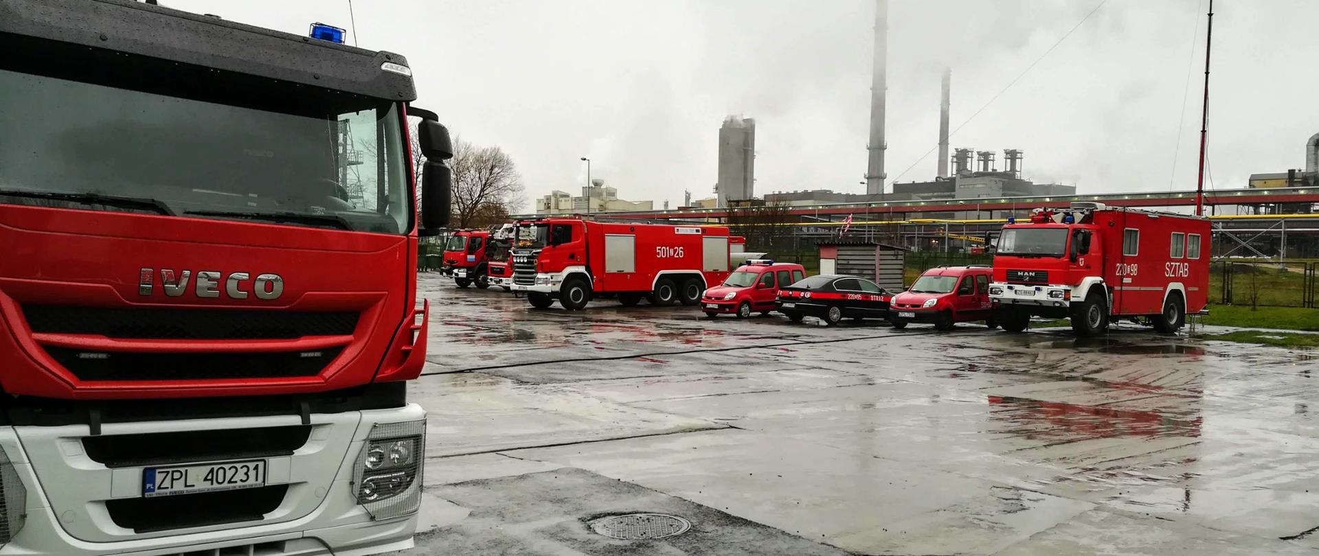 Plac z samochodami staży pożarnej w tle fabryka