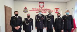 Na zdjęciu na sali konferencyjnej Komendant Powiatowy, oficerowie i trzej druhowie OSP stojący w szeregu w granatowych mundurach galowych