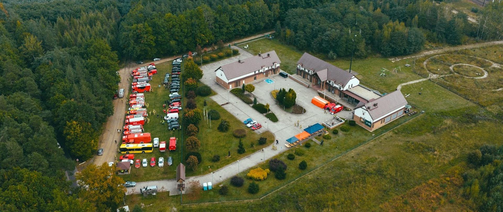 Widok budynków Nadleśnictwa i samochodów w punkcie przyjęcia sił i środków