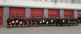 Zdjęcie przedstawia osoby w mundurach stojące przed budynkiem KP PSP Opatów. Większość strażaków posiada zaświadczenia ukończenia kursu.
