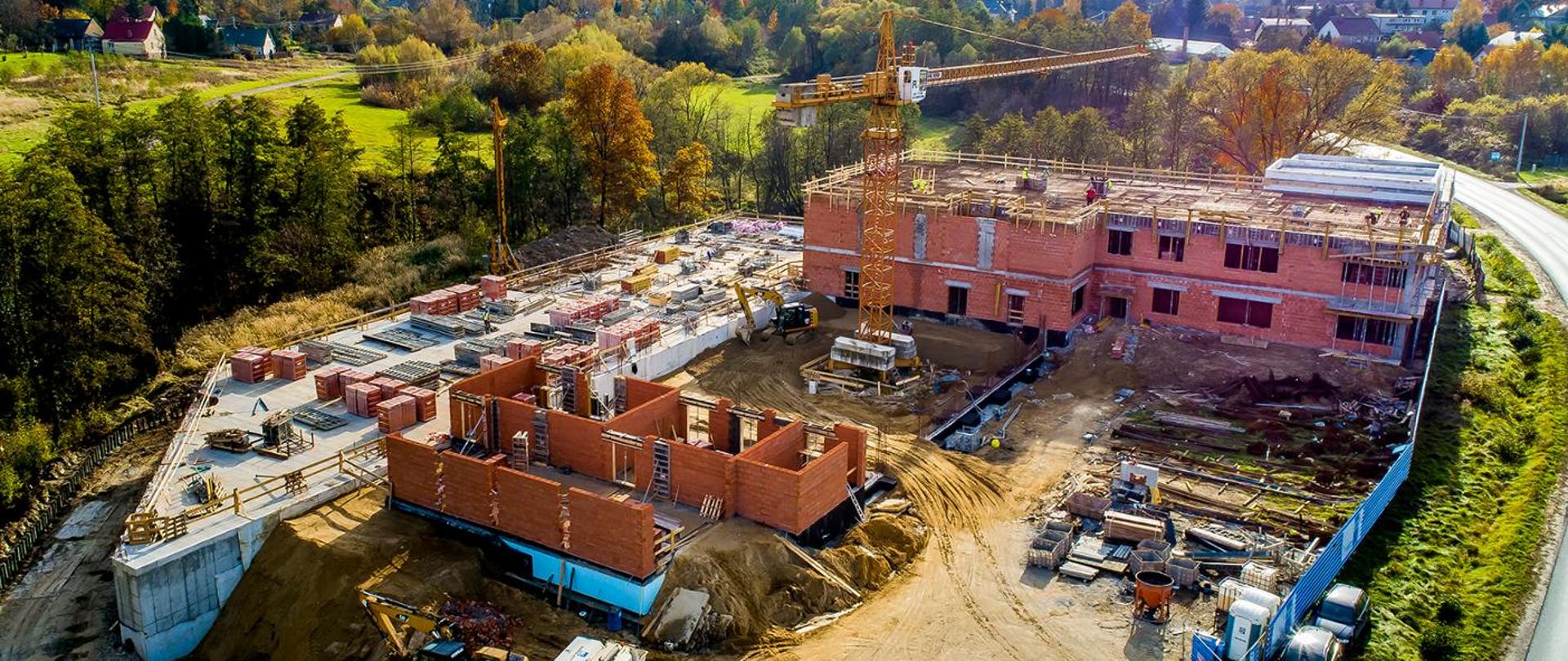 Widok z lotu drona terenu budowy KP PSP w Wieliczce. Dookoła zielony teren.