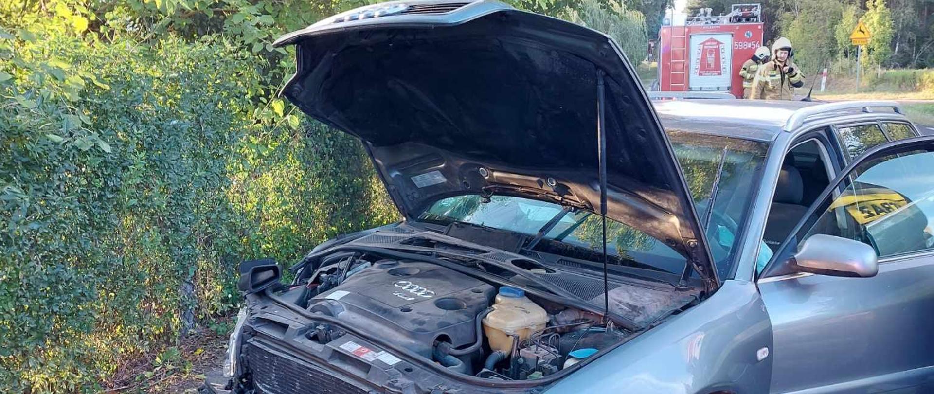 Ciemny samochód z otwartą maską na poboczu