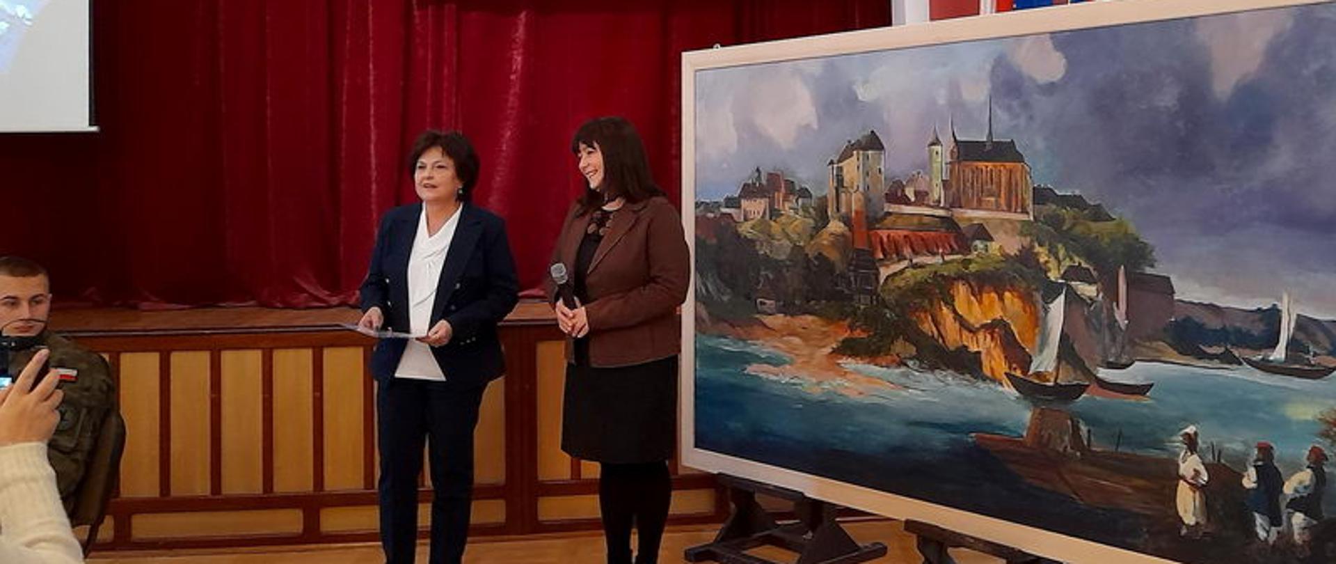 zdjęcie przedstawia dwie panie i obraz, na którym jest namalowany widok Sandomierza