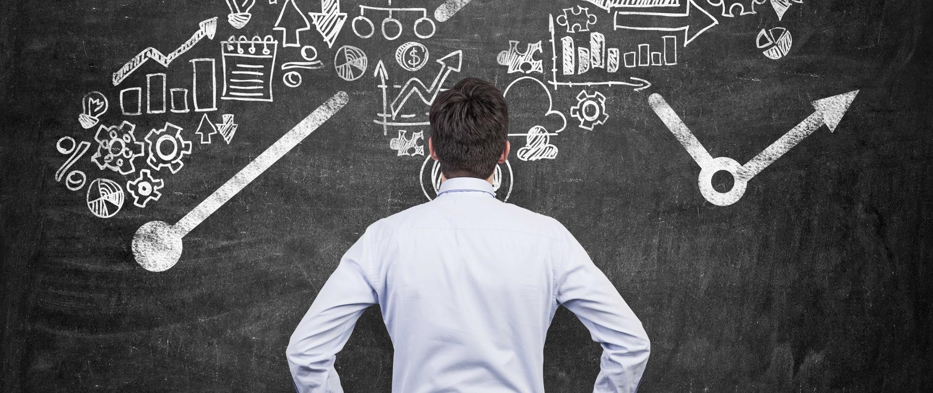 Mężczyzna w białej koszuli patrzy na tablicę ze znakami