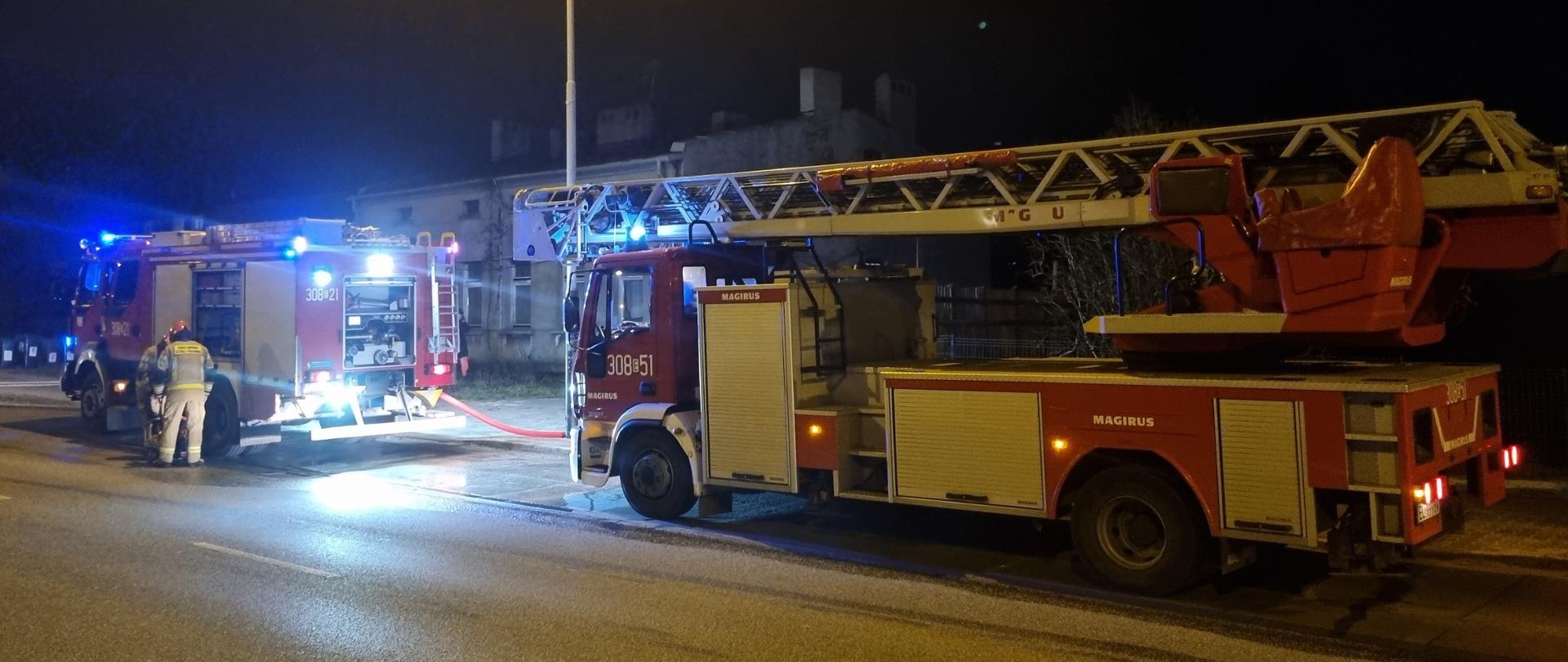 Samochód pożarniczy oraz drabina mechaniczna stojące wzdłuż ulicy przed budynkiem