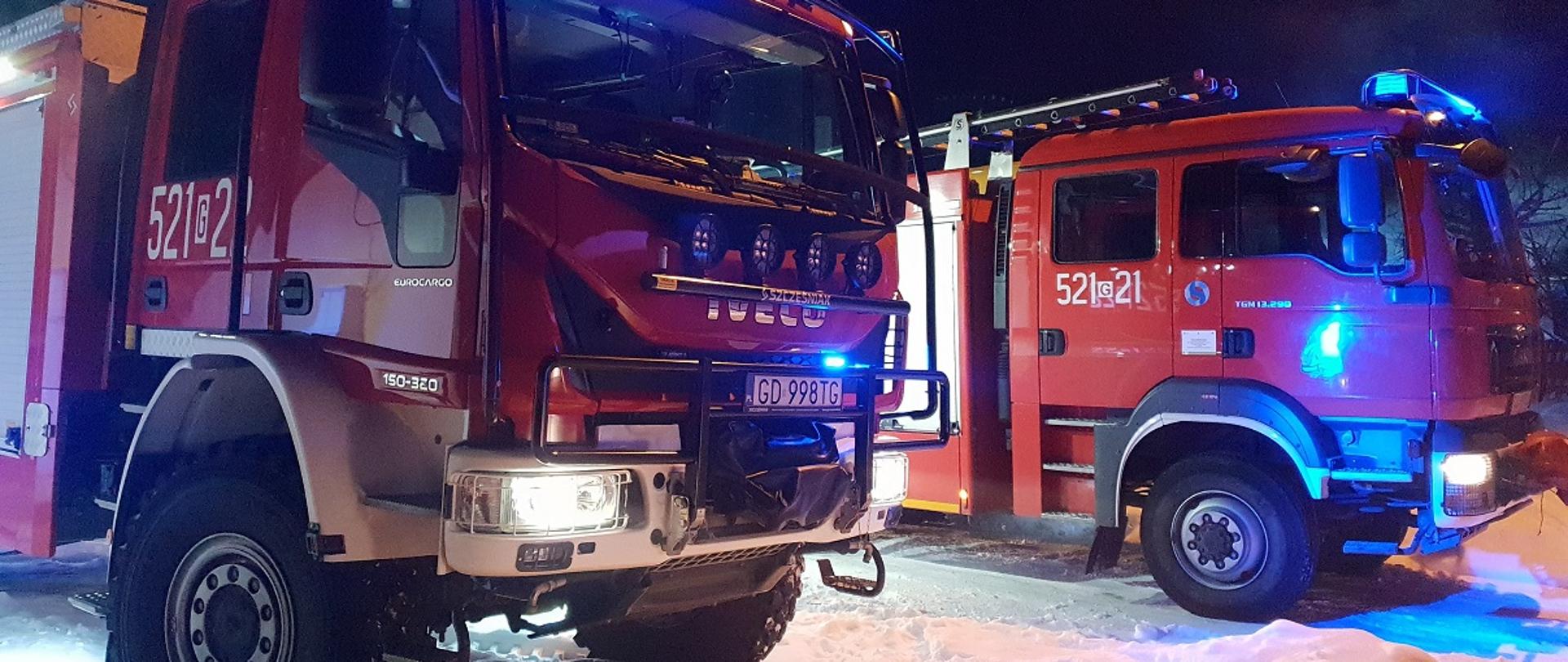Foto przedstawia dwa samochody pożarnicze w trakcie działań ratowniczych, włączone sygnały świetlne.