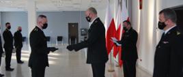 Wręczenie świadectw kursu zawodowego. Zastępca kujawsko-pomorskiego komendanta wojewoódzkiego st. bryg. Slawomir Herbowski wręcza strażakom świadectwa ukończenia kursu zawodowego - pierwszego etapu szkolenia. . Wszyscy strażacy ubrani są w umundurowanie wyjściowe. Towarzyszą im flagi w barwie narodowej.