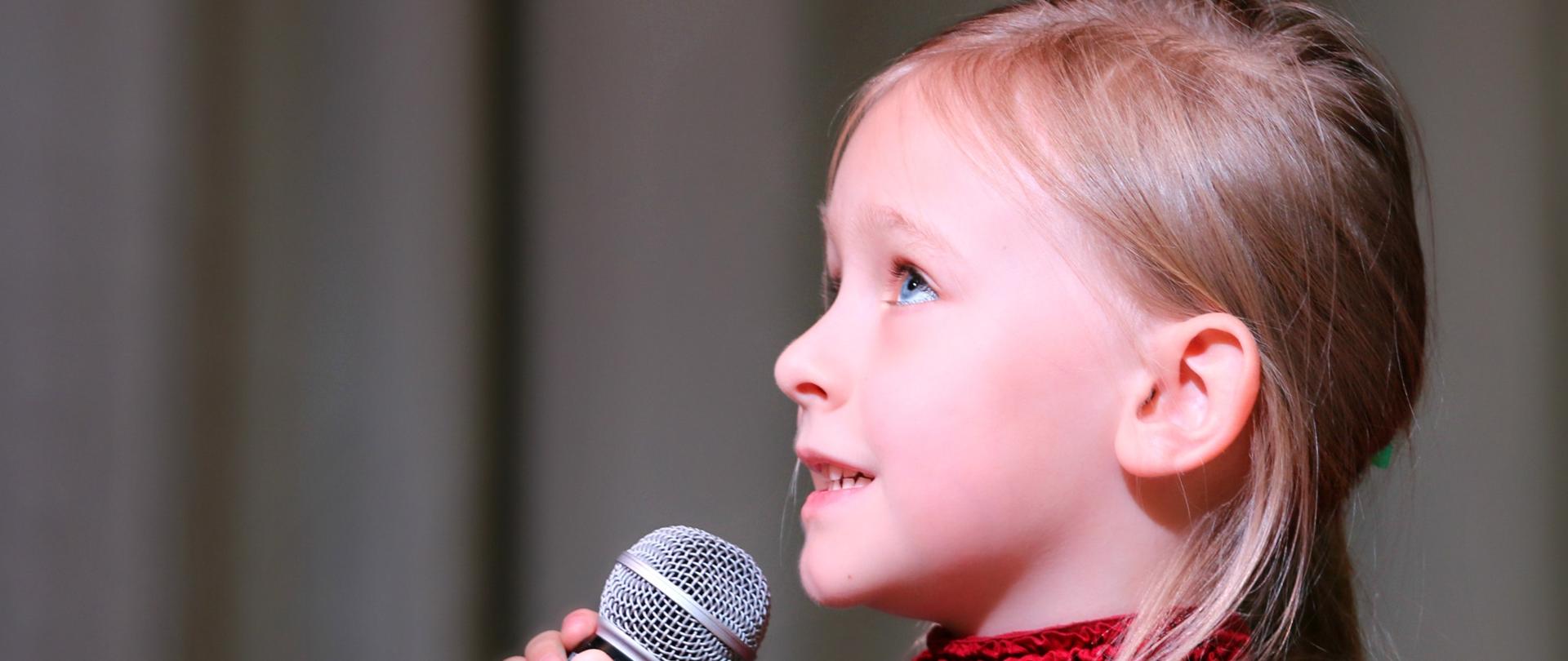 Zdjęcie przedstawiające dziewczynkę trzymającą mikrofon.