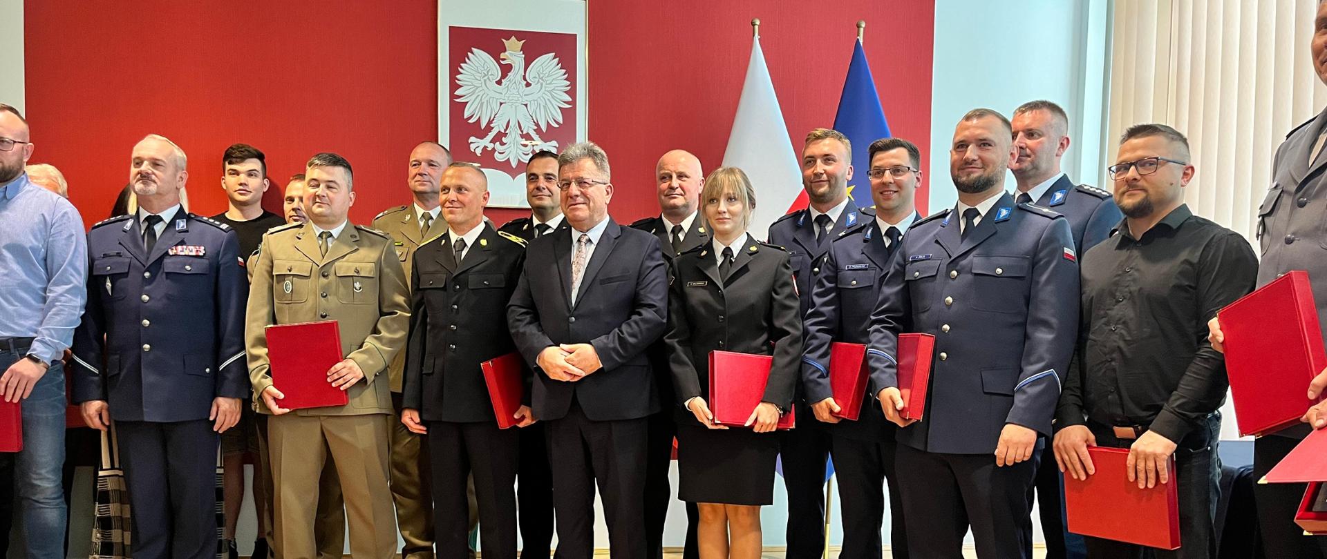 Na zdjęciu widzimy grupę ludzi pozujących do fotografii z upominkami w rękach.