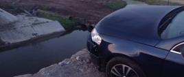 samochód stoi nad betonowym przepustem w którym jest woda