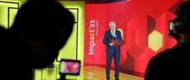Wicepremier i minister rozwoju, pracy i technologii Jarosław Gowin podczas otwarcia wiosennej edycji Impact"21, z tyłu za jego placami logo Impact'21 na czerwonym tle