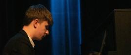Zdjęcie przedstawia pianistę Jana Glinkowskiego występującego na scenie podczas koncertu z okazji jubileuszu szkoły.