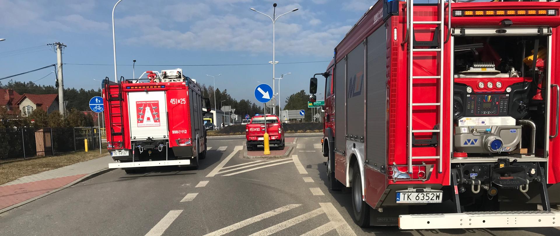 Na zdjęciu widać trzy samochody strażackie zaparkowane na ulicy Samsonowicza w Ostrowcu Św. Zdjęcie wykonane w porze dziennej. Droga jest zablokowana przez samochody strażackie. Miejsce wykonania zdjęcia znajduje się w pobliżu wycieku po prawej stronie.