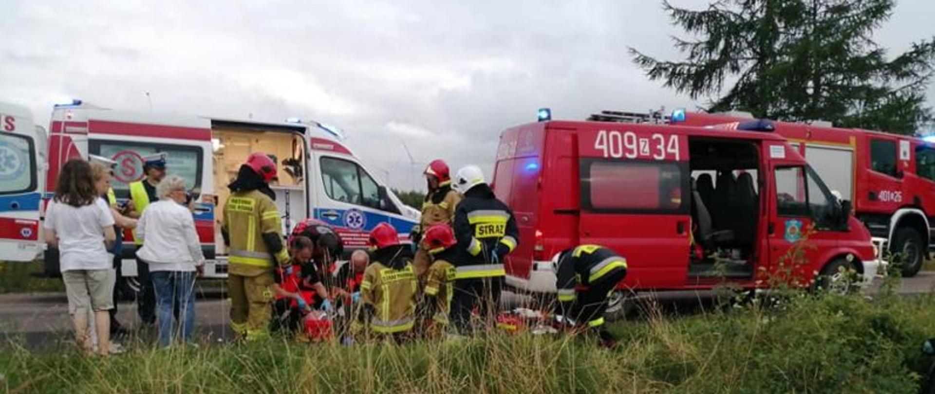 Zdjęcie przedstawia teren działań. Widać na nim zgrupowanie ludzi, pojazdy gaśnicze oraz ratownicze. Jest dzień. Trwa akcja ratunkowa.