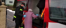 Na zdjęciu druh OSP w Ruszelczycach pomaga starszej osobie podczas wsiadania do samochodu OSP w celu transportu do punktu szczepień
