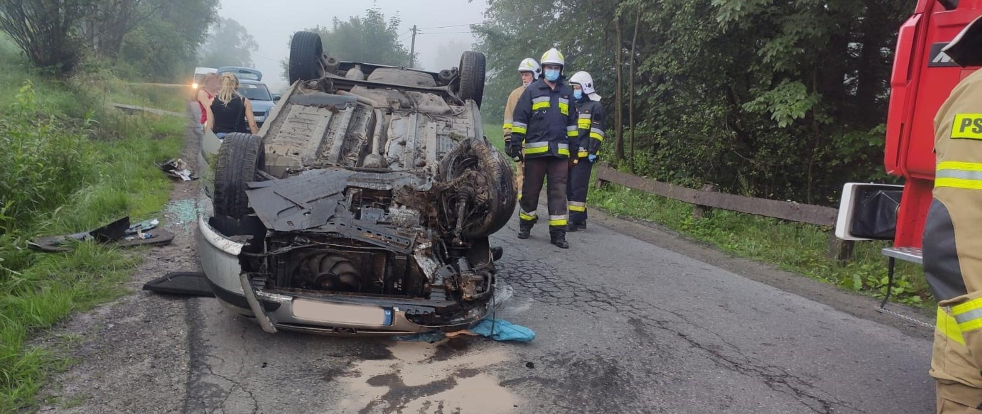Zdjęcie przedstawia samochód po dachowaniu leżący na dachu.