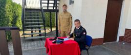 Ślubowanie nowo przyjętego strażaka. Na placu KP PSP Radziejów odbyło się ślubowanie nowo przyjętego strażaka. Zdjęcie przedstawia strażaka, który podpisuje akt mianowania w obecności Komendanta Powiatowego PSP