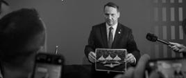 Minister Radosław Sikorki shows a photo of a drone at the meeting with the press