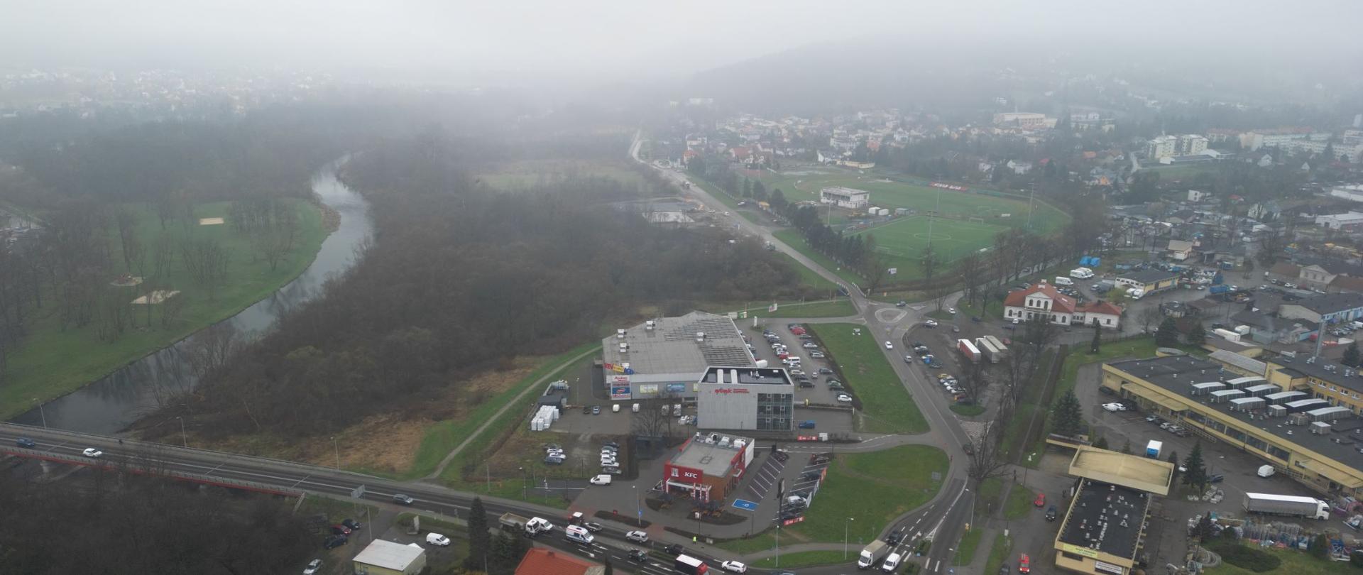 DK28 południowa obwodnica Wadowic, teren budowy przyszłej trasy, na pierwszym planie rondo, w oddali masyw Beskidu Małego, po lewej rzeka Skawa