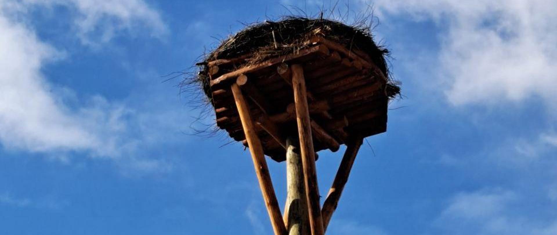 na le nieba widoczny słup z gniazdem bociana 