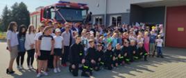 Zdjęcie grupowe osób przed samochodem pożarniczym podczas uroczystego apelu