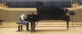 Uczennica gra na fortepianie na scenie sali koncertowej PSM