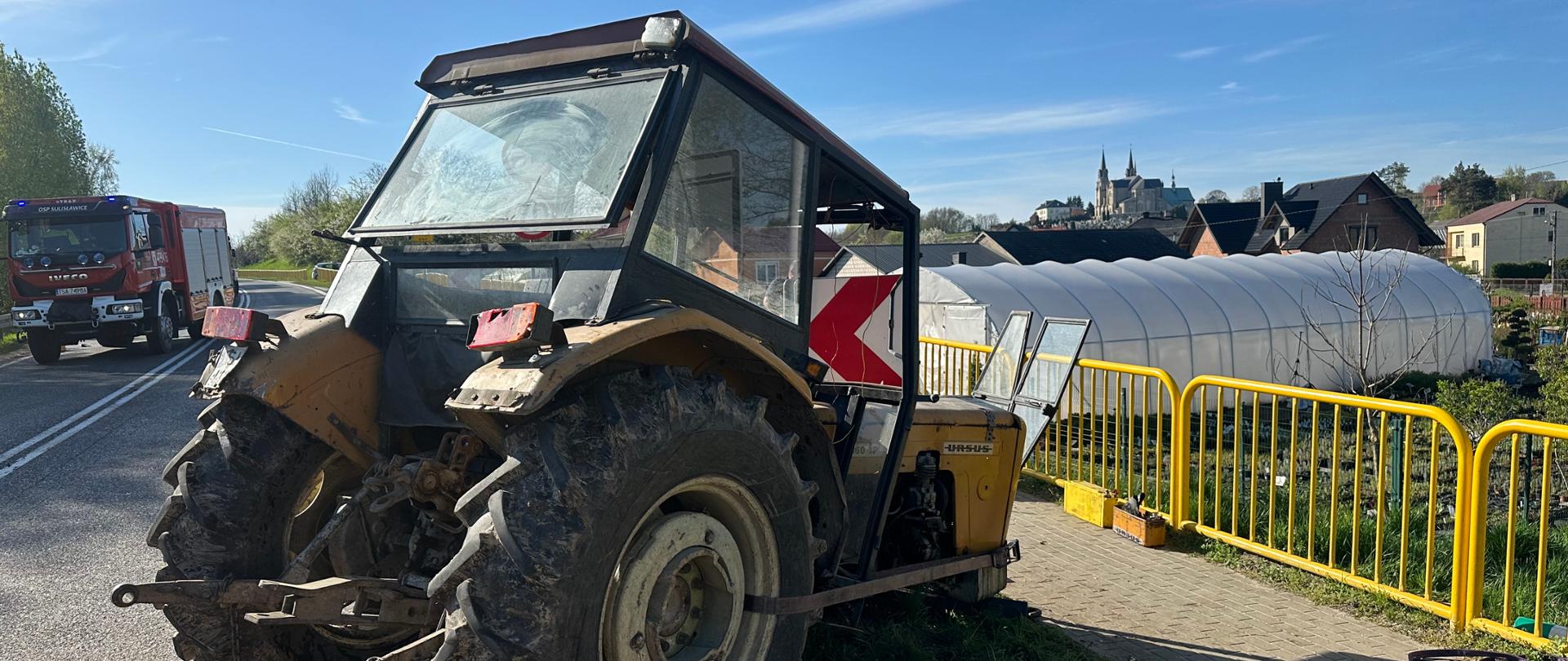 Na zdjęciu widać ciągnik rolniczy Ursus, uszkodzony, wokół rozlany olej hydrauliczny. W tle widać samochód strażacki. 