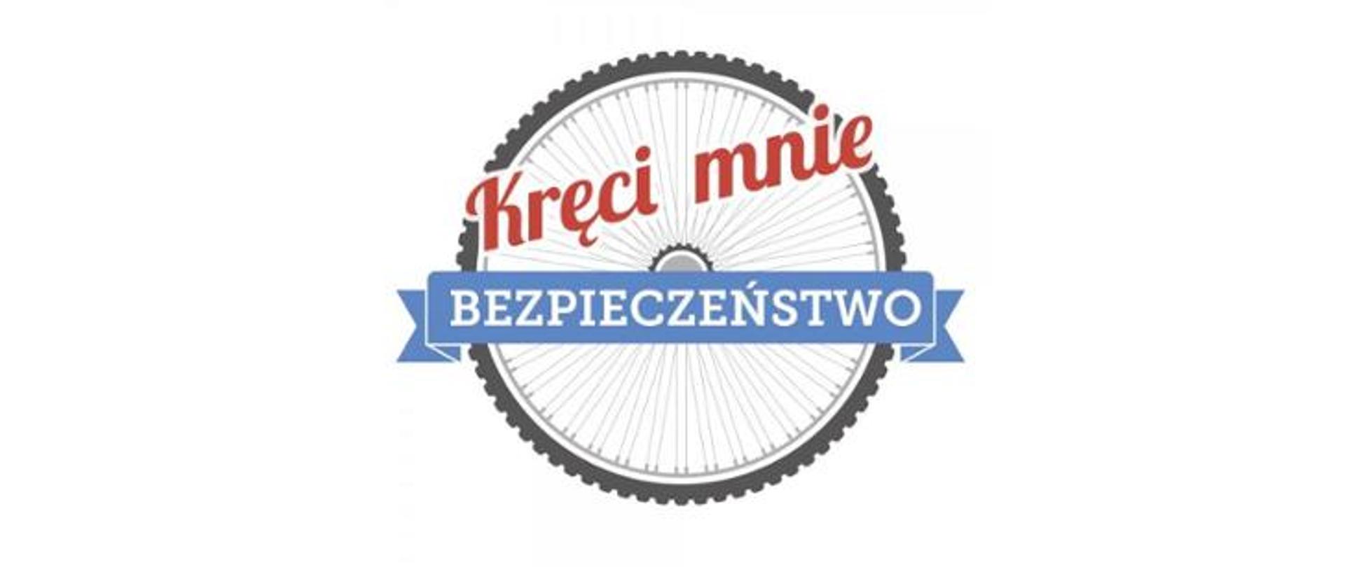 Zdjęcie przedstawia logo promujące akcję „Kręci mnie bezpieczeństwo”. Na białym tle znajduje się koło rowerowe. Przed nim w jego górnej połowie umieszczony jest napis w kolorze czerwonym kręci mnie. W dolnej polowe znajduje się natomiast druga część hasła promującego akcję - bezpieczeństwo. Napis bezpieczeństwo wykonany jest w formie białych liter na niebieskim tle. 