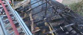 Spalony budynek gospodarczy - widok z drabiny mechanicznej na spalony dach i wnętrze budynku