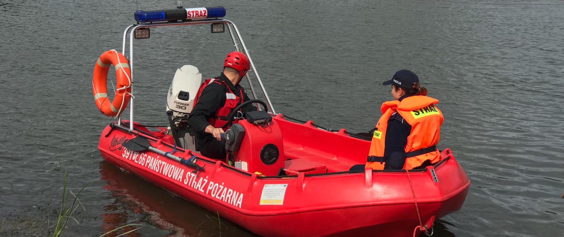 Strażak i policjantka w łodzi na rzece.