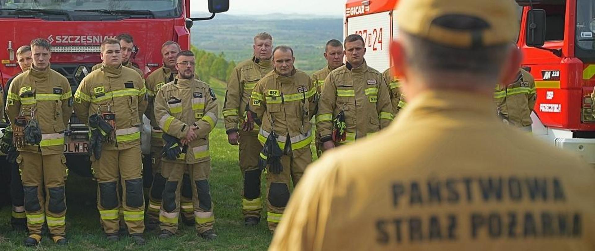 Strażacy stojący w dwuszeregu podczas odprawy przed ćwiczeniami.