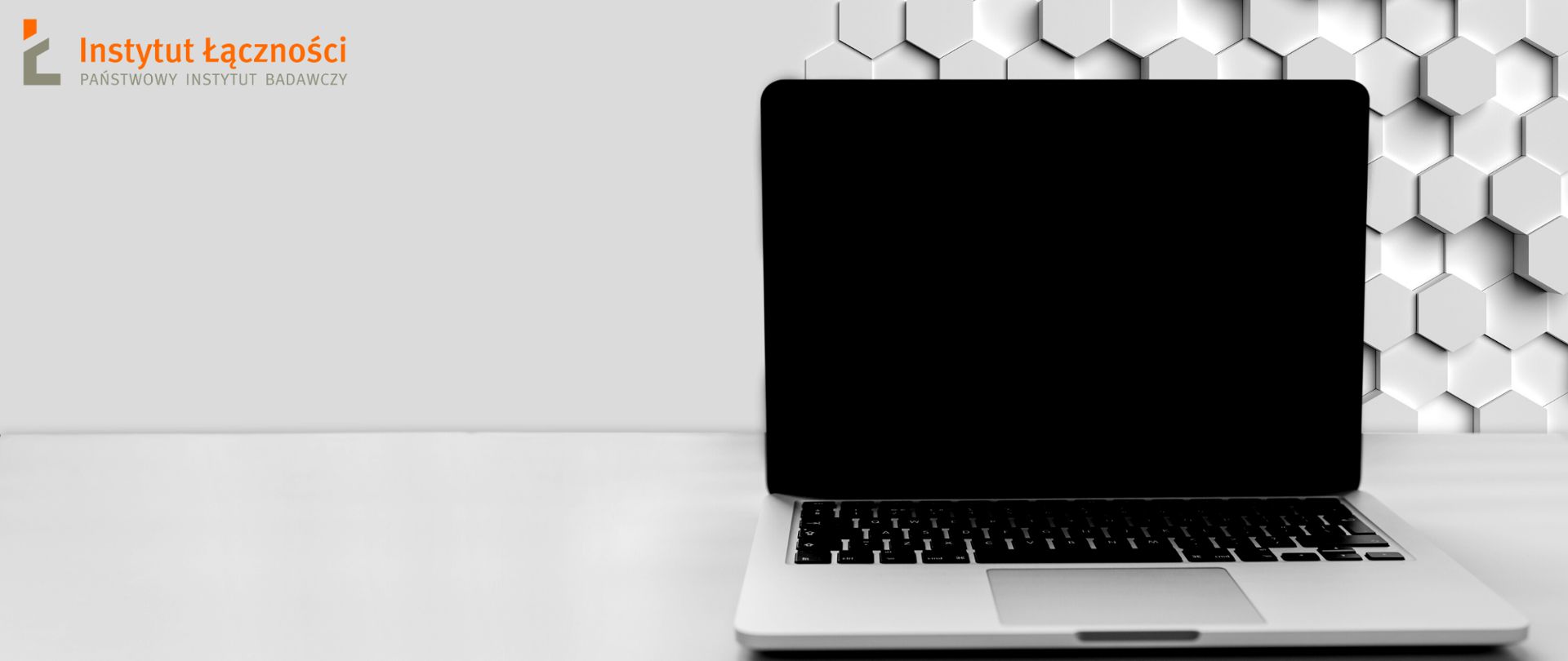Laptop stojący na blacie, w rogu logo Instytutu Łączności