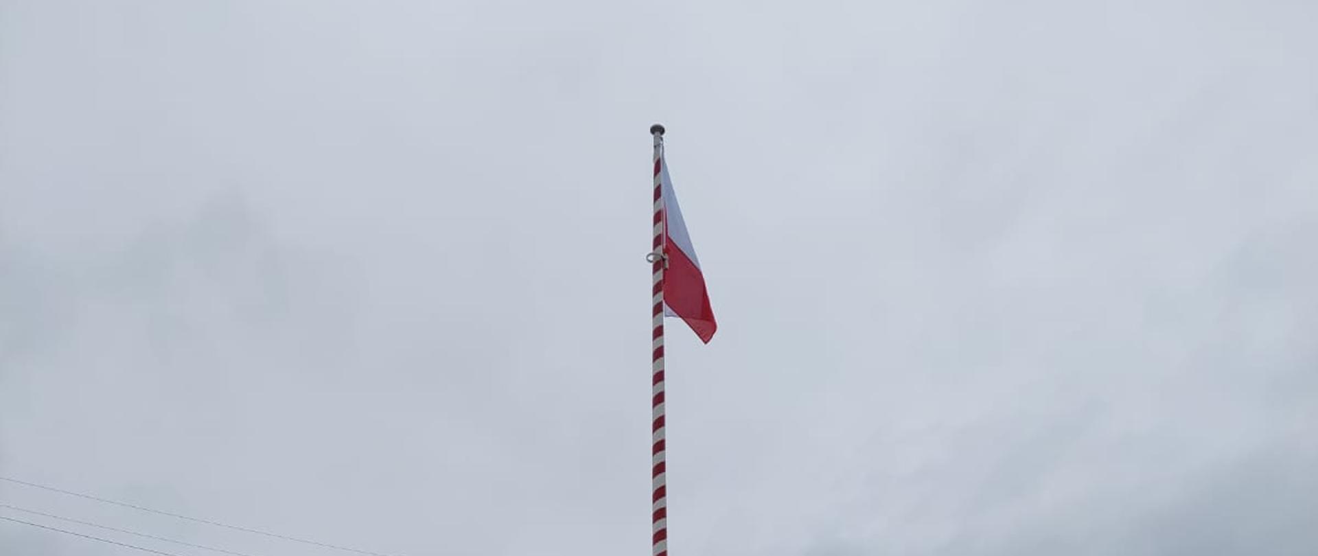 Strażacy JRG 6 podczas uroczystej zbiórki podnoszą flagę Polski na maszt.