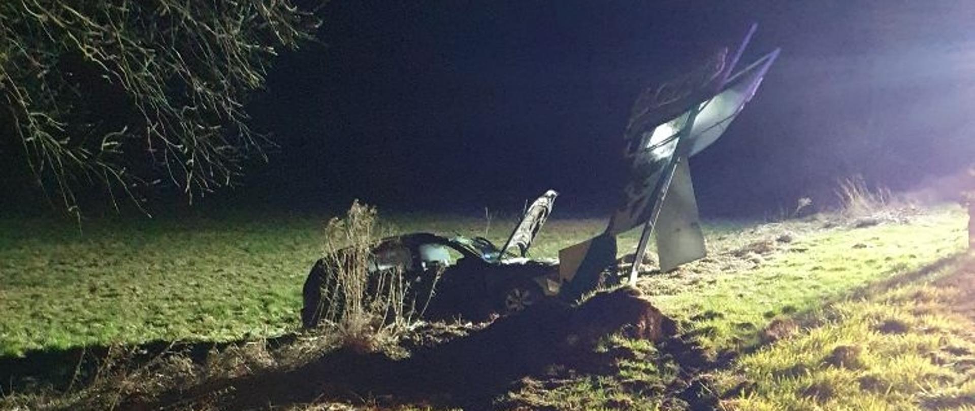 Zdjęcie wykonano w porze nocnej, po prawej stronie zdjęcia jest zniszczona reklama przydrożna w wyniku uderzenia samochodu osobowego, na tej reklamie jest część napisu Pełczyce zaprasza, w środkowej części zdjęcia jest samochód umieszczony bokiem prawa strona pojazdu w którym otworzyły się kurtyny powietrzne, poryta ziemia przed pojazdem