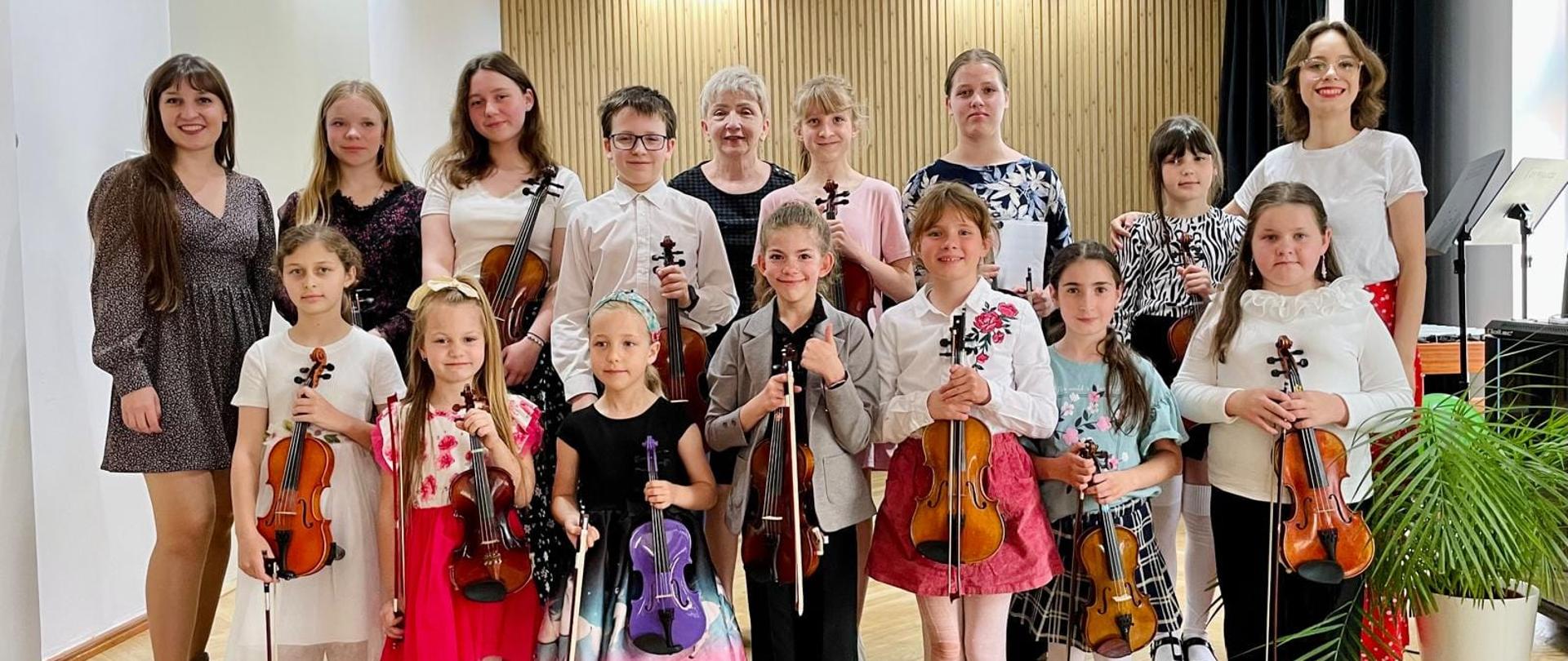 Galeria 22 zdjęć z koncertu klas skrzypiec uczniów p. N. Mierzwy i p. K. Lizurej, który odbył się 03 czerwca 2025 w auli PSM w Kłodzku. Młodzi uczniowie grają na skrzypcach w sali koncertowej