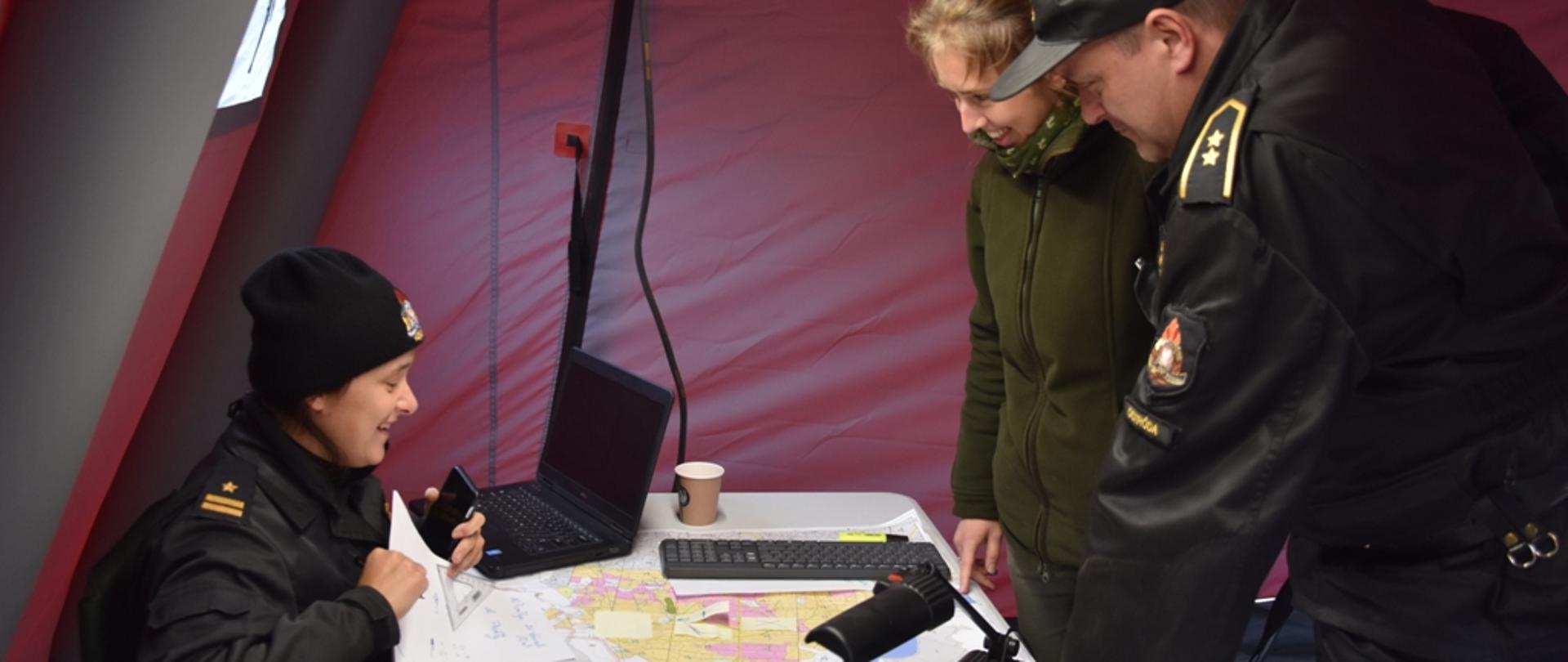 Strażacy wspólnie z pracownikiem Nadleśnictwa ustalają sposób przecinki przeciwpożarowej. 