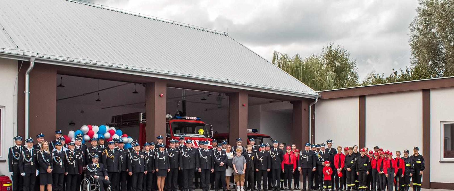 Przed nowo otwartą remizą stoi tłum umundurowanych druhów osp.