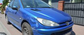 Masłowo, ulica Matejki. Samochód osobowy uderzył w ogrodzenie posesji. Na zdjęciu zaparkowany na chodniku samochód osobowy marki peugeot koloru błękitnego. Za nim strażak, policjant i "cywil", z prawej strony - zabudowania 