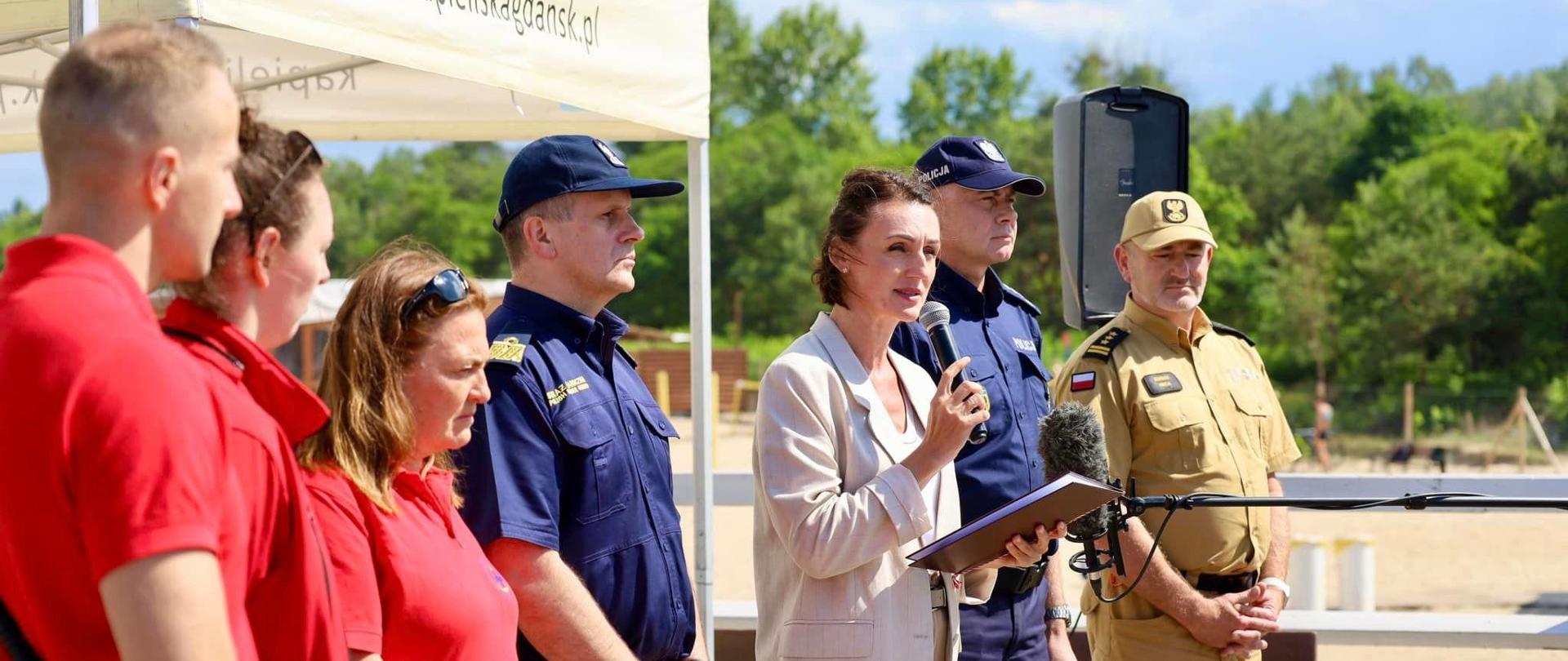 grupa osób stoi na molo, są tam policjanci, strażnicy graniczni, ratownicy wodni i wojewoda