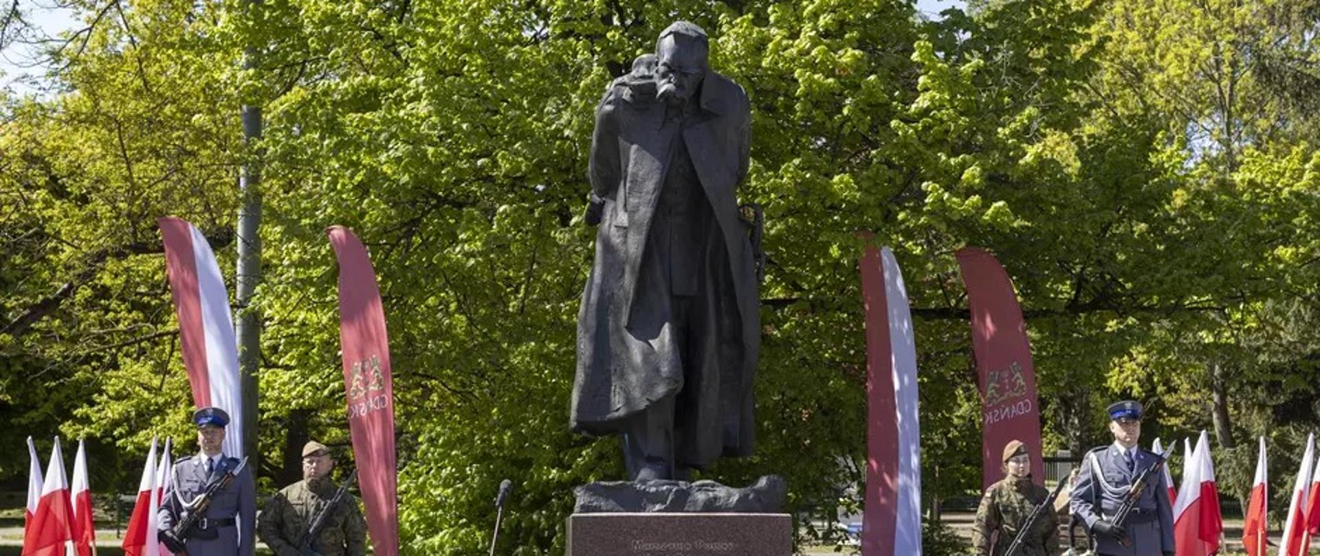 pomnik Piłsudskiego, wokół flagi biało czerwone i żołnierze