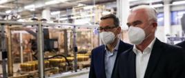 Premier Mateusz Morawiecki i prezes firmy idą przez zakład produkcyjny.